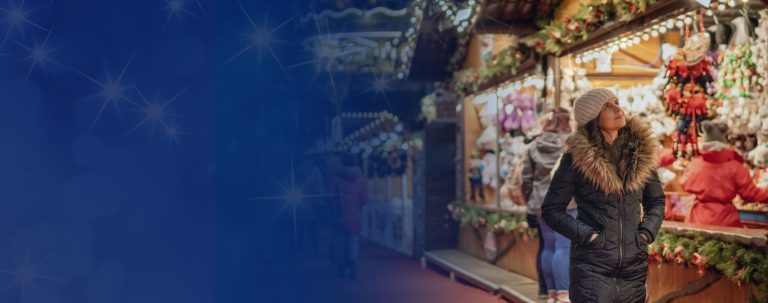A vibrant Christmas market at night, featuring illuminated festive stalls, a sparkling ice rink, and visitors enjoying the attractions.